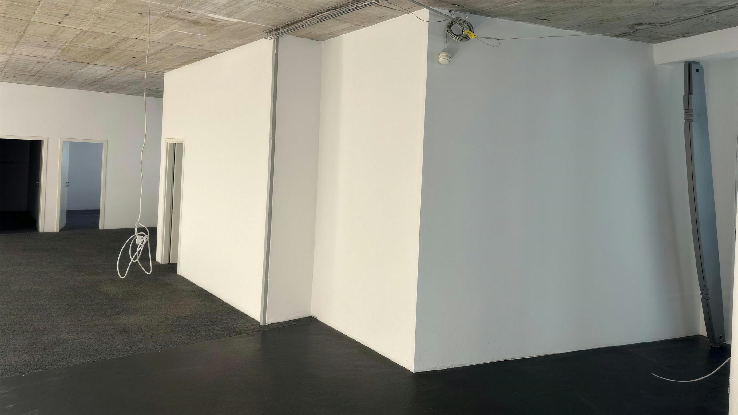 Chantier réalisé : cloisons neuves en plâtre peintes en blanc, angles nets, dans un plateau de bureaux sous dalle béton